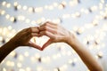 Heart shaped hands with decoration lights as background Royalty Free Stock Photo