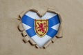 Heart shaped hole torn through paper, showing Nova Scotia flag Royalty Free Stock Photo