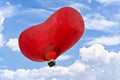 Heart-shaped hot air balloon flying over a blue sky with white clouds Royalty Free Stock Photo