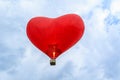 Heart-shaped hot air balloon flying over a blue sky with white clouds Royalty Free Stock Photo