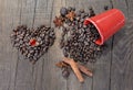 Heart shaped jewel in beans of coffee forming a heart next to a spilled red cup full of beans