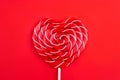 A heart-shaped lollipop on a red background. Valentine`s Day concept.