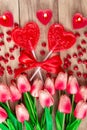 Heart shaped lollipops on wooden background with heart shaped candles lined with tulips flowers. Festive background Royalty Free Stock Photo