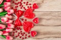 Heart shaped lollipops on wooden background with heart shaped candles lined with tulips flowers. Festive background Royalty Free Stock Photo