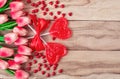 Heart shaped lollipops on wooden background, lined with tulips flowers. Festive background to the Valentine`s day. Royalty Free Stock Photo