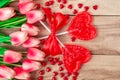 Heart shaped lollipops on wooden background, lined with tulips flowers. Festive background to the Valentine`s day. Royalty Free Stock Photo