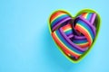 Heart shaped mold and bright rainbow ribbon on color background, space for text. Symbol of gay community