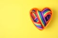 Heart shaped mold and bright rainbow ribbon on color background, top view. Symbol of gay community