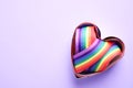 Heart shaped mold and bright rainbow ribbon on color background, top view. Symbol of gay community