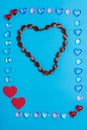 Heart-shaped necklace in a frame made of pebbles of hearts on a blue background. Royalty Free Stock Photo