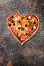 Heart shaped not ready pizza with tomatoes and mozzarella for Valentines Day on vintage concrete background. Food