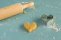 Heart-shaped raw cookie and cookie cutter. Rolling pin. Royalty Free Stock Photo