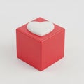 A heart-shaped object on top of a red cube against a white background Royalty Free Stock Photo