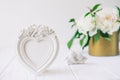 Heart shaped photoframe with plaster flowers, statuette of two antique little lovely angels on the white wooden table with bouquet Royalty Free Stock Photo