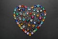 Heart shaped pile of different beautiful gemstones on background, flat lay