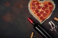 Heart shaped pizza with mozzarella, sausagered with a bottle of wine and wineglas on rusty background Royalty Free Stock Photo