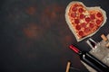 Heart shaped pizza with mozzarella, sausagered with a bottle of wine and wineglas. Valentines day greeting card on rusty backgroun Royalty Free Stock Photo