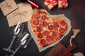 Heart shaped pizza with mozzarella, sausagered, wine bottle, two wineglass, gift box on rusty background Royalty Free Stock Photo