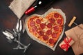 Heart shaped pizza with mozzarella, sausagered, wine bottle, two wineglass, gift box on rusty background Royalty Free Stock Photo