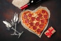 Heart shaped pizza with mozzarella, sausagered, wine bottle, two wineglass, gift box on rusty background Royalty Free Stock Photo