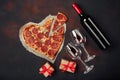 Heart shaped pizza with mozzarella, sausagered, wine bottle and two wineglass. Valentines day greeting card on rusty background. Royalty Free Stock Photo