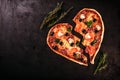 Heart shaped pizza with tomatoes and mozzarella for Valentines Day on vintage black background. Food concept of romantic