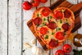 Heart shaped pizza for Valentines Day over white wood, above view, side border table scene Royalty Free Stock Photo