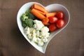 Heart shaped plate with assorted fresh vegetables, top view.