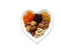 Heart shaped plate with different dried fruits and nuts on white background, top view Royalty Free Stock Photo