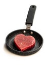 Heart shaped raw beef meat on small frying pan isolated on white. Healthy lifestyle or organic food concept for meat lovers Royalty Free Stock Photo