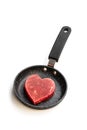 Heart shaped raw beef meat with spices on small frying pan isolated on white. Healthy lifestyle or organic food concept for meat Royalty Free Stock Photo