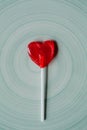 Heart shaped red lollipop on blue background. Heart shaped red candy for design.