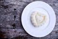 Heart-shaped rice on white plate and wooden floor Royalty Free Stock Photo