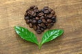 Heart shaped roasted coffee beans and leaves Royalty Free Stock Photo