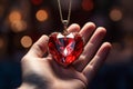 A heart-shaped ruby pendant in a womans hand. Luxurious red precious jewelry with red crystal Royalty Free Stock Photo