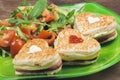 Heart shaped sandwiches with ham and cheese with fresh vegetable on a plate, closeup Royalty Free Stock Photo