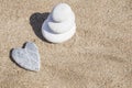 Heart shaped stone and stack of pebbles on balance on sandy beach Royalty Free Stock Photo