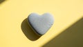 Heart-shaped stone on yellow background Royalty Free Stock Photo