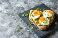 a heart shaped toast with avocado and eggs on top of a gray tile Royalty Free Stock Photo