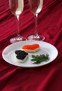 Heart shaped toasts with red and black caviar and two glasses of champagne on white plate on red drapery Royalty Free Stock Photo