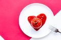 Heart shaped tomato in tomato paste on a white plate. Bright, minimalistic still life scene.