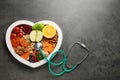 Heart shaped tray with healthy products and stethoscope on grey background, top view. Royalty Free Stock Photo