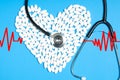 Heart of white pills and stethoscope on blue background Royalty Free Stock Photo