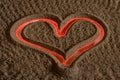 Heart shaped symbol drawn in sand with red backlight Royalty Free Stock Photo