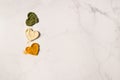 Heart shapes of dried basil, ginger and turmeric powder spices on marble background