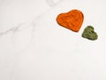 Heart shapes of dried basil and paprika powder spices on marble background