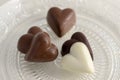 Heart shapped chocolate sweets, brown and white color, transparent retro plate with pralines