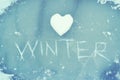 Heart from snow and the word WINTER scratched on ice. Winter theme.