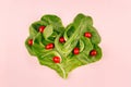 Heart of spring healthy food - cherry tomatoes and leaves spinach on pink background. Valentine`s day backdrop. Royalty Free Stock Photo