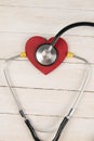 Heart with stethoscope on white wooden table. Medical concept. Top views with clear space